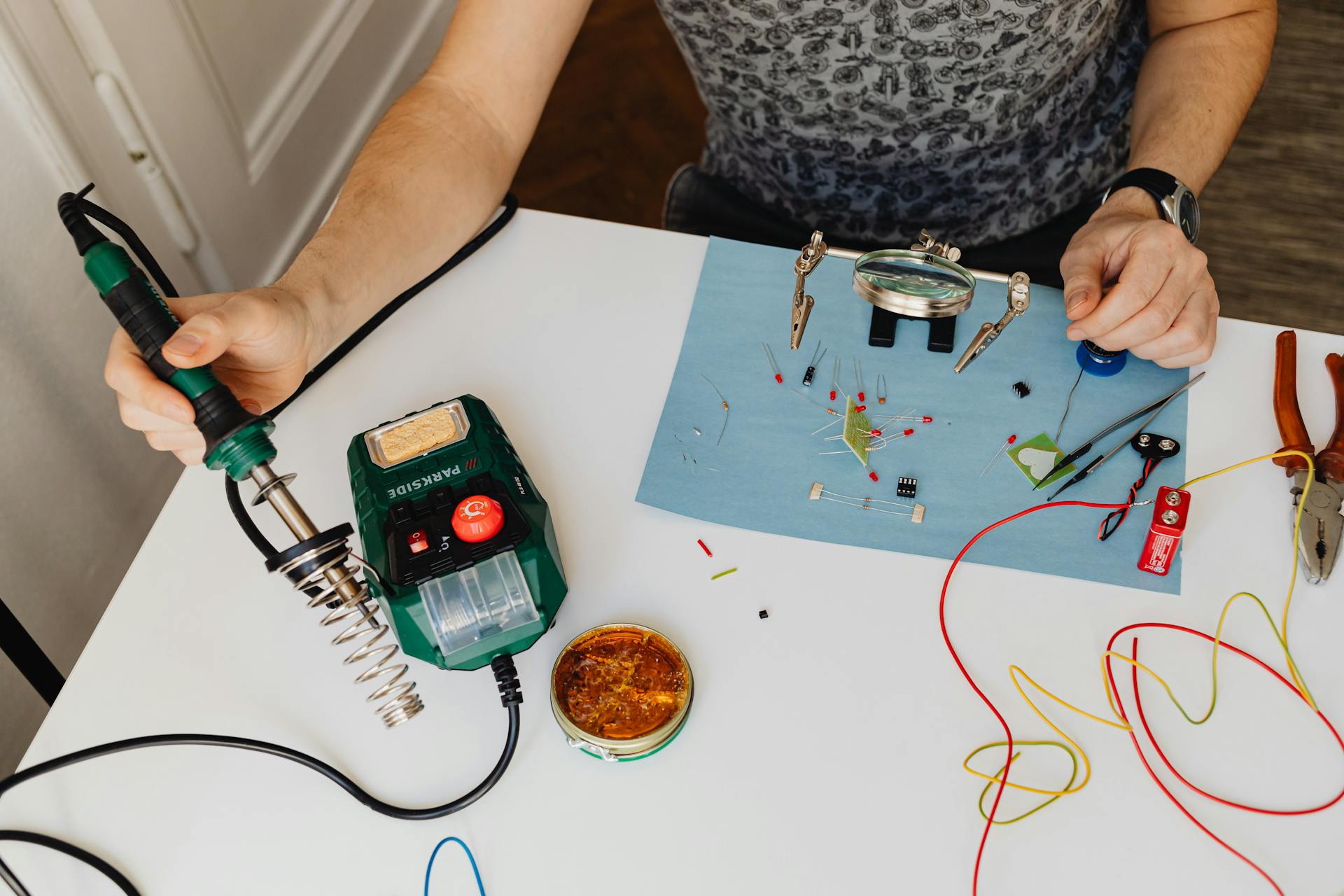 Įrankiai ir atsarginės dalys namų remontui ant medinio stalo, rankos montuoja komponentus